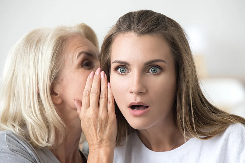 Old,mother,whispering,in,ear,of,adult,daughter,telling,secret